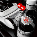 A bottle of San Pellegrino Mineral Water in the 'Pellegrino' variant, styled in a Porsche Cayenne center console next to a silver gear shift knob and a black gear selector, with a selective color effect leaving the bottle and console in sharp focus.

The Mars23arth symbol shines in red.