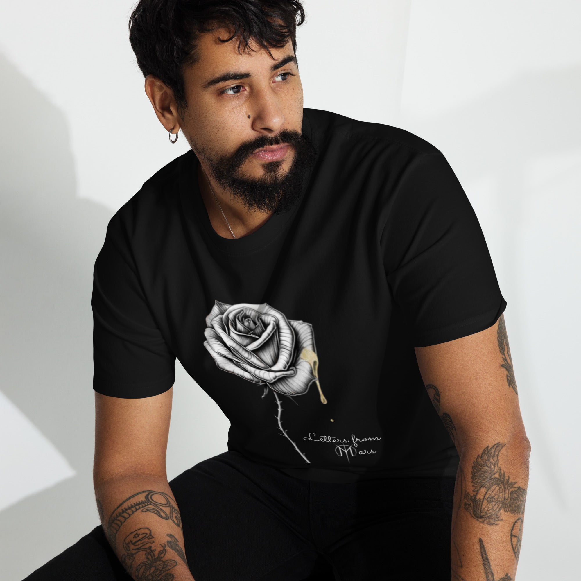 Man wearing a black t-shirt with a Letters from mars rose design on a white background