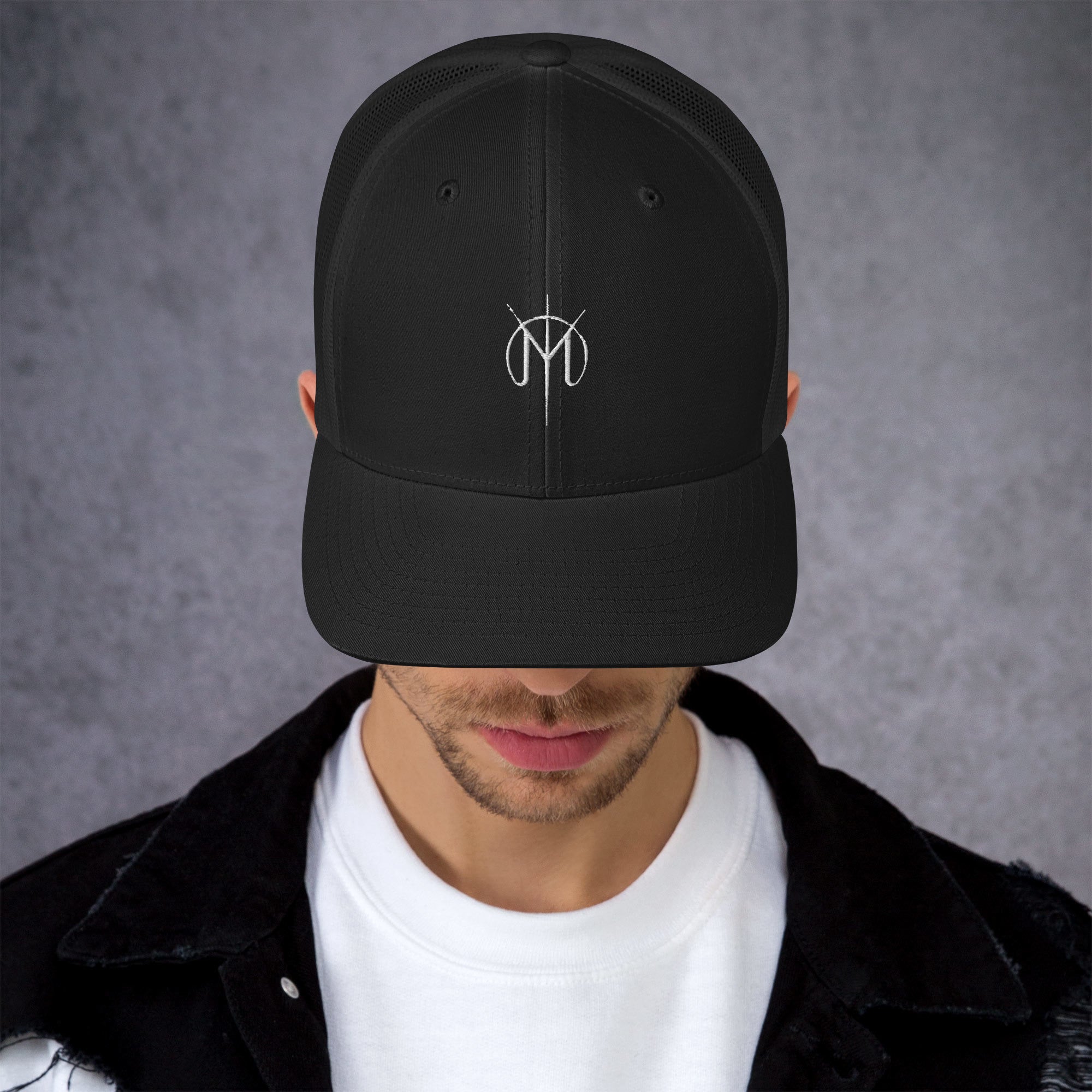 Person wearing a black cap with a Letters from Mars M logo on a gray background