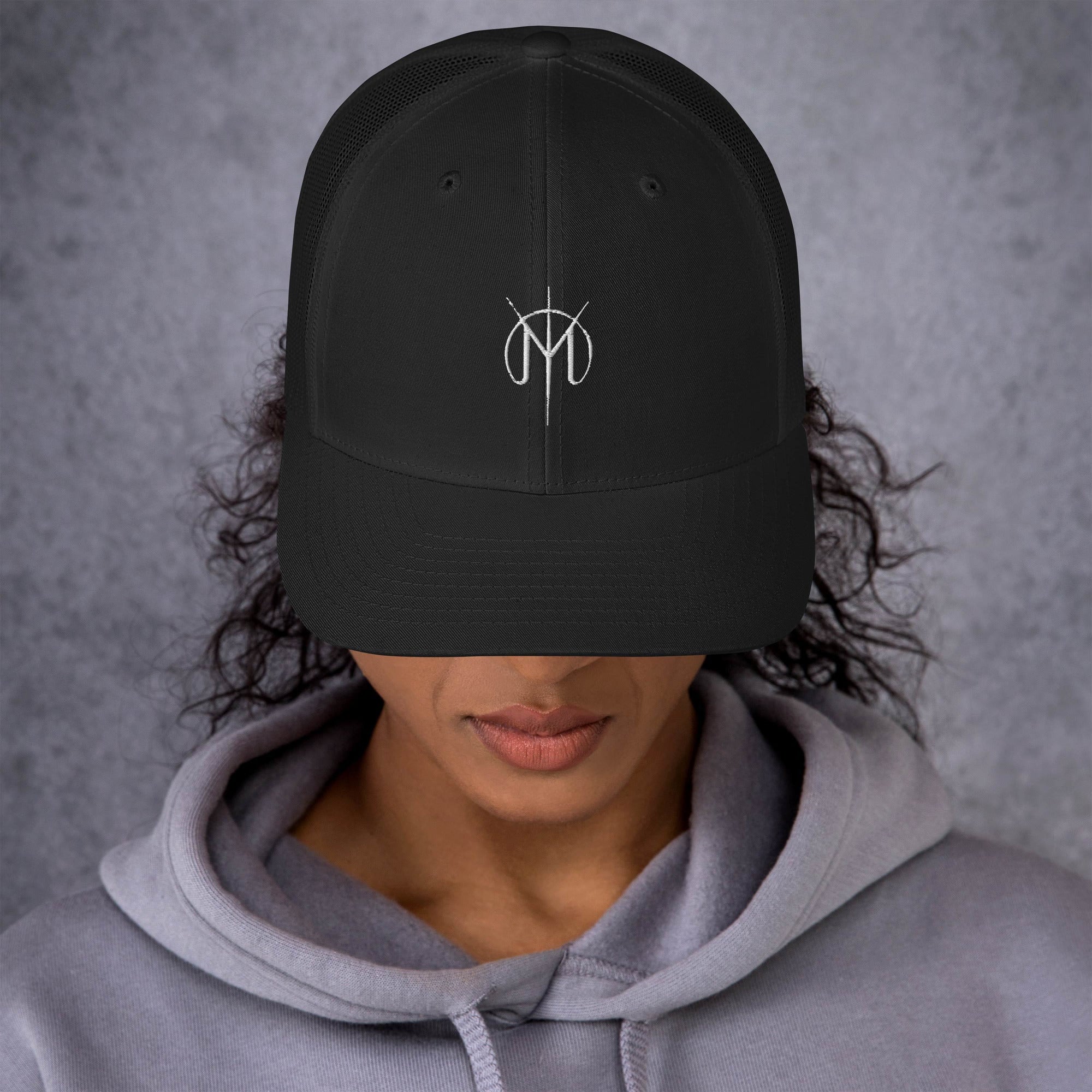 Person wearing a dark gray cap with a Letters from Mars M logo on a gray background