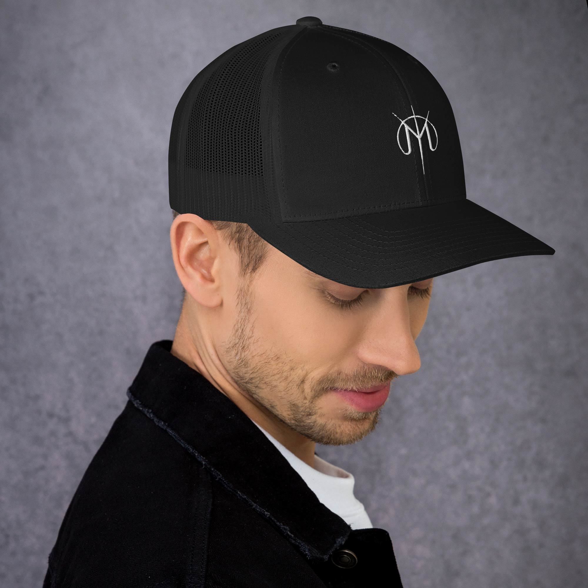Man wearing a black cap with a Letters from Mars M logo on a gray background